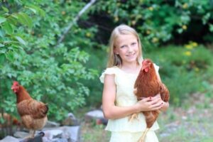 Ein Mädchen hat ein Huhn auf dem Arm